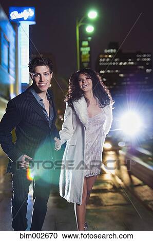 Elegant couple walking on urban street at night View Large Photo Image Stock Image - Elegant couple walking on urban street at night. Fotosearch