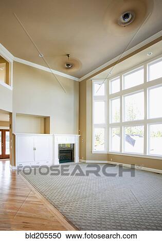 Stock Image - Empty living room with tall windows. Fotosearch
