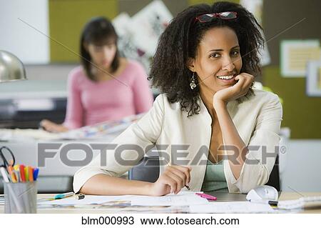 Stock Image - Ethiopian businesswoman sitting at desk. Fotosearch