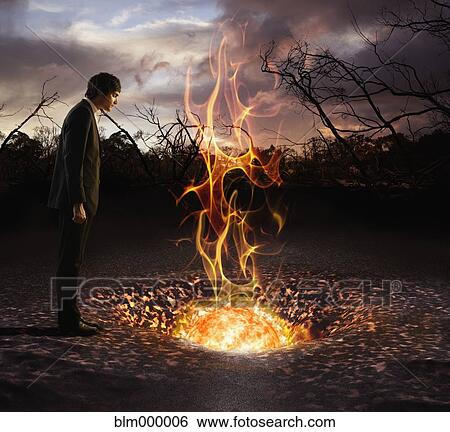 Stock Photograph - European businessman looking at fire ball in hole. Fotosearch