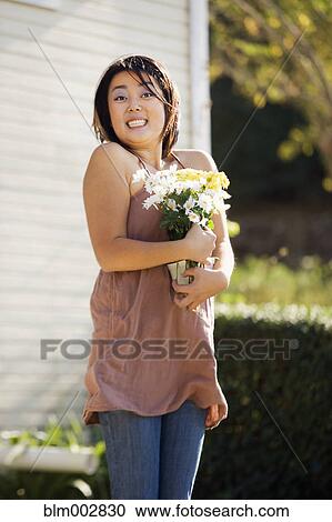 Stock Image - Excited Chinese woman holding bouquet of flowers. Fotosearch