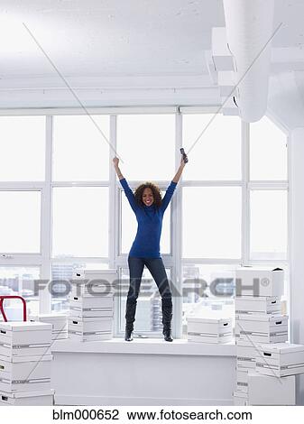 Stock Image - Excited woman moving into new office. Fotosearch