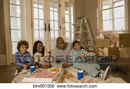 Stock Image - Family eating on floor in new home. Fotosearch