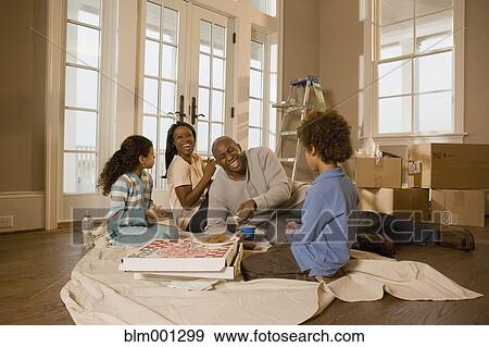 Stock Photo - Family eating on floor in new home. Fotosearch