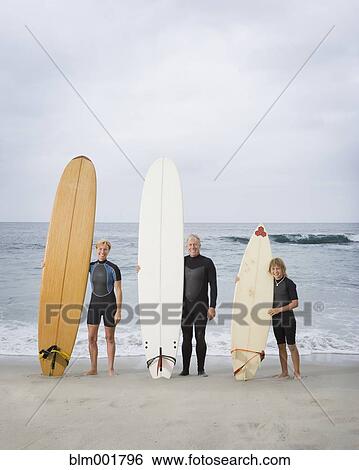 Stock Photograph - Family holding surfboards at beach. Fotosearch