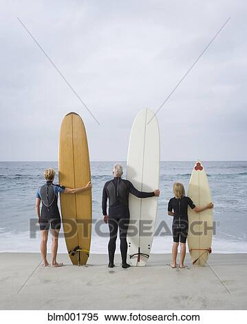 Family holding surfboards at beach View Large Photo Image Stock Photography - Family holding surfboards at beach. Fotosearch