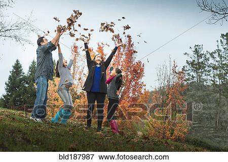 Stock Photo - Family playing in autumn leaves. Fotosearch