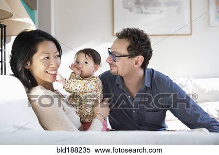 Stock Photography - Family relaxing on sofa. Fotosearch