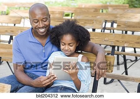 Stock Image - Father and daughter using tablet computer. Fotosearch