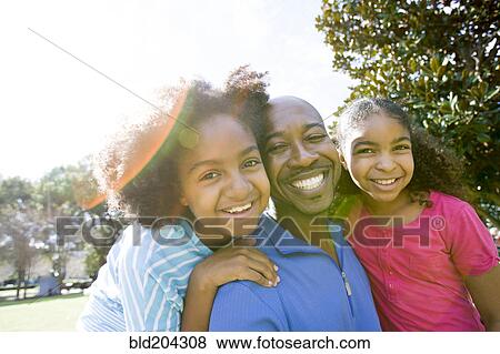 Father and daughters smiling in park View Large Photo Image Stock Photo - Father and daughters smiling in park. Fotosearch