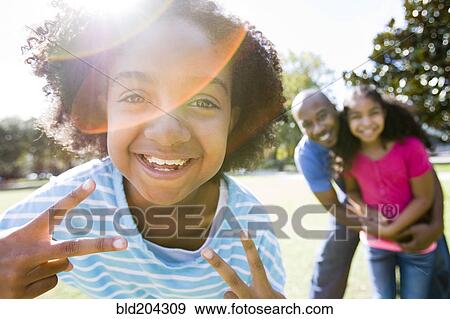 Stock Photo - Father and daughters smiling in park. Fotosearch