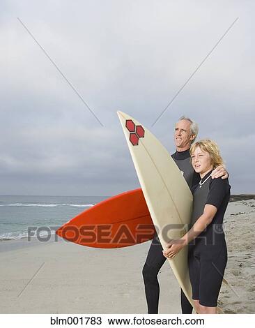Father and son holding surfboards at beach View Large Photo Image Stock Image - Father and son holding surfboards at beach. Fotosearch