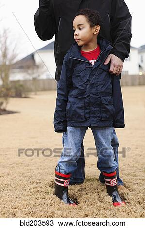 Stock Image - Father and son standing in field. Fotosearch