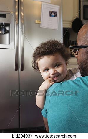 Father holding baby in kitchen View Large Photo Image Stock Photo - Father holding baby in kitchen. Fotosearch