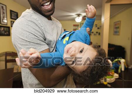 Father playing with baby in living room View Large Photo Image Stock Photo - Father playing with baby in living room. Fotosearch