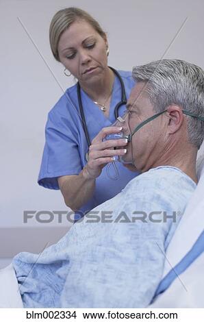 Female medical professional adjusting patient's oxygen mask View Large Photo Image Picture - Female medical professional adjusting patient's oxygen mask. Fotosearch