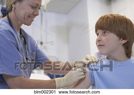 Stock Image - Female medical professional preparing boy for shot. Fotosearch