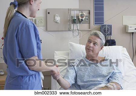 Stock Image - Female medical professional shaking hands with patient. Fotosearch