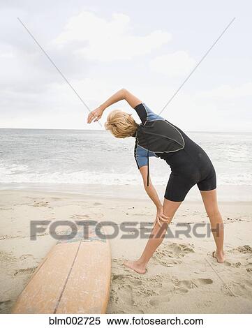 Female surfer stretching at beach View Large Photo Image Stock Photography - Female surfer stretching at beach. Fotosearch