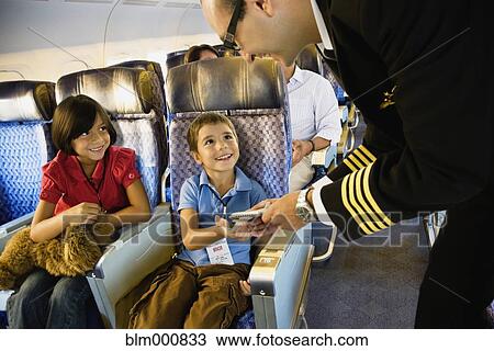 Stock Image - Flight attendant helping children on airplane. Fotosearch
