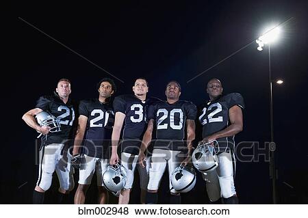 Stock Photo - Football players in uniform holding helmets. Fotosearch