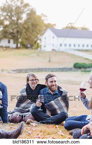 Stock Image - Friends drinking wine in rural field. Fotosearch