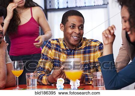 Stock Photography - Friends playing board game at party. Fotosearch