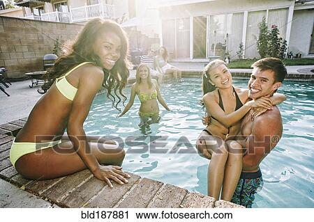 Stock Image - Friends playing in swimming pool. Fotosearch