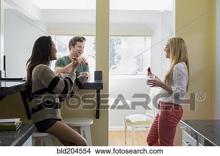 Picture - Friends relaxing together in kitchen. Fotosearch