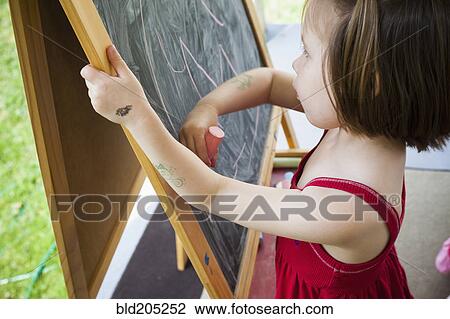 Stock Image - Girl drawing on blackboard easel. Fotosearch