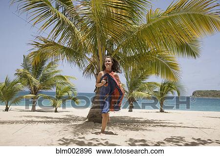 Stock Photograph - Girl in sarong running on beach. Fotosearch