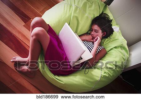 Girl using laptop in beanbag View Large Photo Image Stock Photo - Girl using laptop in beanbag. Fotosearch