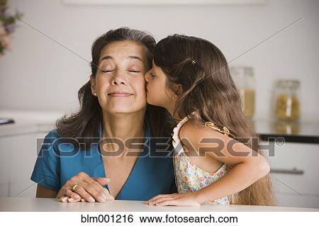 Stock Photograph - Granddaughter kissing Hispanic grandmother. Fotosearch