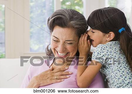 Granddaughter whispering to Hispanic grandmother View Large Photo Image Stock Photograph - Granddaughter whispering to Hispanic grandmother. Fotosearch