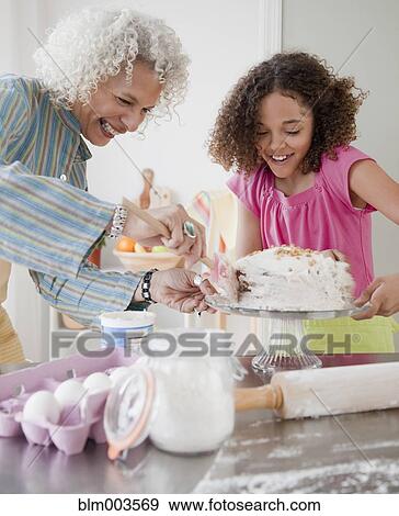 Stock Photo - Grandmother and granddaughter frosting cake. Fotosearch