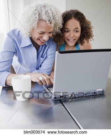 Picture - Grandmother and granddaughter using laptop. Fotosearch