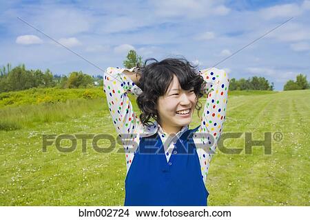 Happy Asian woman standing in park View Large Photo Image Picture - Happy Asian woman standing in park. Fotosearch