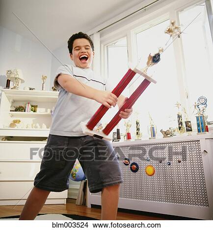 Happy Hispanic boy holding trophy in bedroom View Large Photo Image Picture - Happy Hispanic boy holding trophy in bedroom. Fotosearch