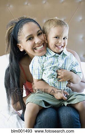 Stock Image - Happy mother holding son on lap. Fotosearch