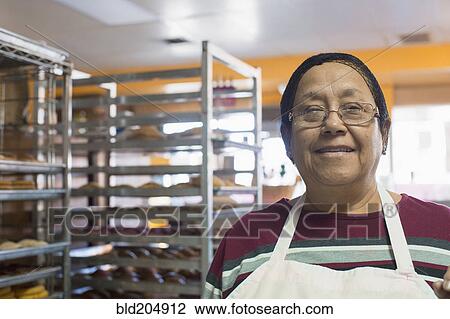 Stock Image - Hispanic baker smiling in kitchen. Fotosearch