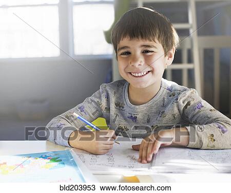 Stock Image - Hispanic boy doing homework at desk. Fotosearch