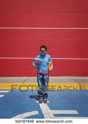 Stock Photo - Hispanic boy holding popcorn and soda at movie theater. Fotosearch