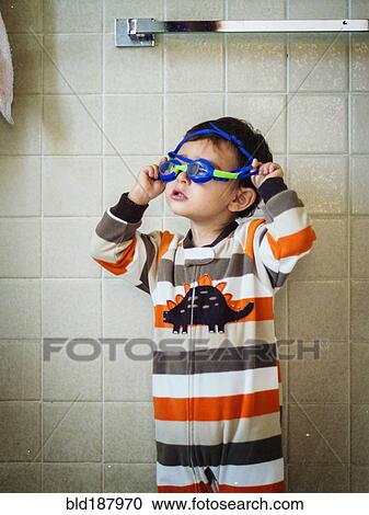 Stock Image - Hispanic boy playing with goggles in bathroom. Fotosearch