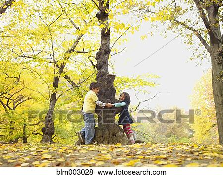 Stock Photo - Hispanic brother and sister playing outdoors in autumn. Fotosearch