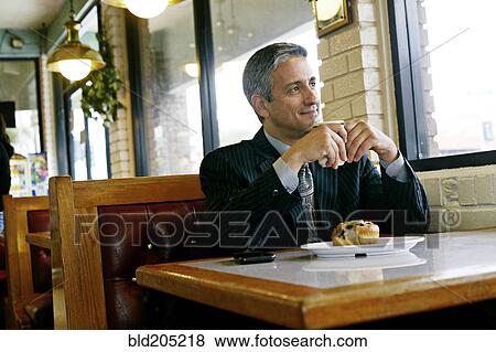 Stock Photo - Hispanic businessman having coffee in restaurant. Fotosearch