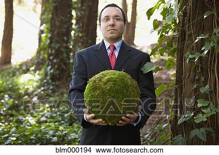 Picture - Hispanic businessman holding ball of moss. Fotosearch