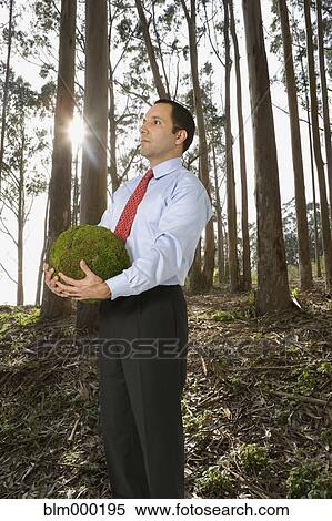 Stock Photography - Hispanic businessman holding ball of moss. Fotosearch