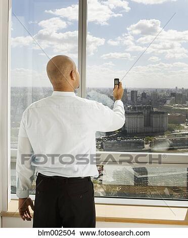 Hispanic businessman holding up cell phone View Large Photo Image Picture - Hispanic businessman holding up cell phone. Fotosearch