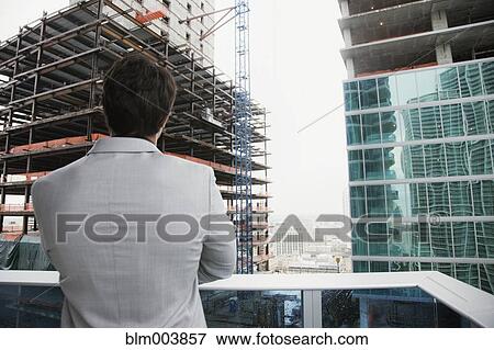 Hispanic businessman looking at skyscraper construction from balcony View Large Photo Image Stock Photo - Hispanic businessman looking at skyscraper construction from balcony. Fotosearch