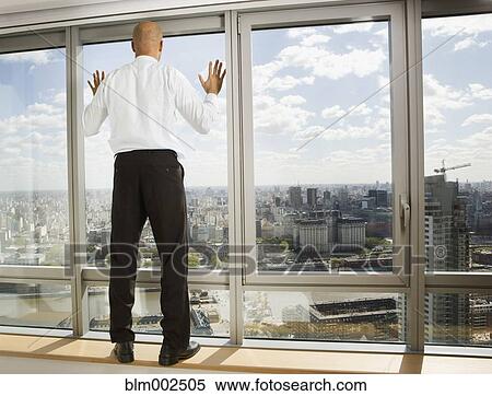 Stock Photography - Hispanic businessman looking out window. Fotosearch